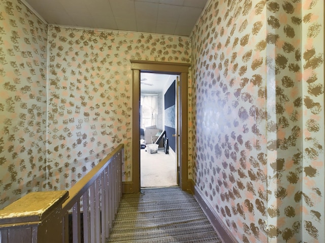 hall with dark carpet and ornamental molding