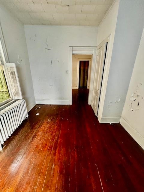 spare room with dark hardwood / wood-style floors and radiator