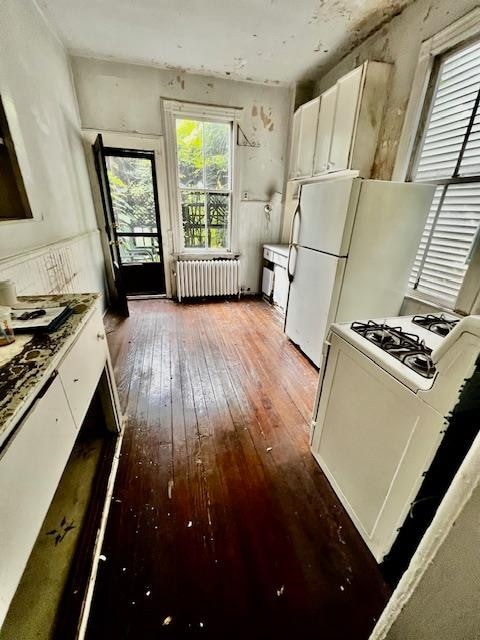 kitchen featuring white cabinetry, wood-type flooring, white appliances, and radiator