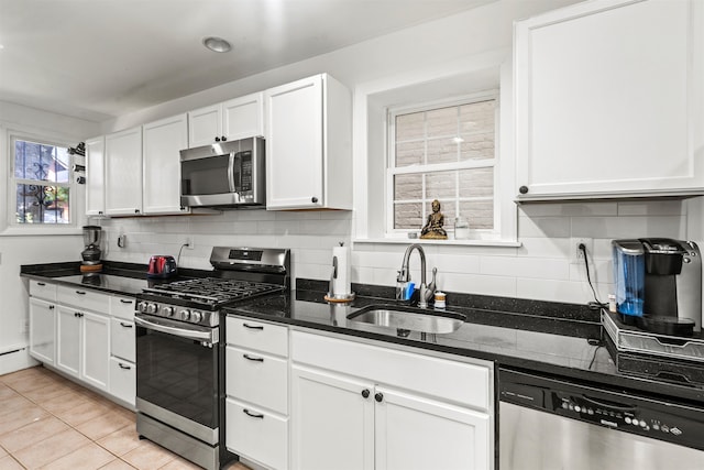 kitchen featuring appliances with stainless steel finishes, decorative backsplash, sink, white cabinets, and dark stone countertops