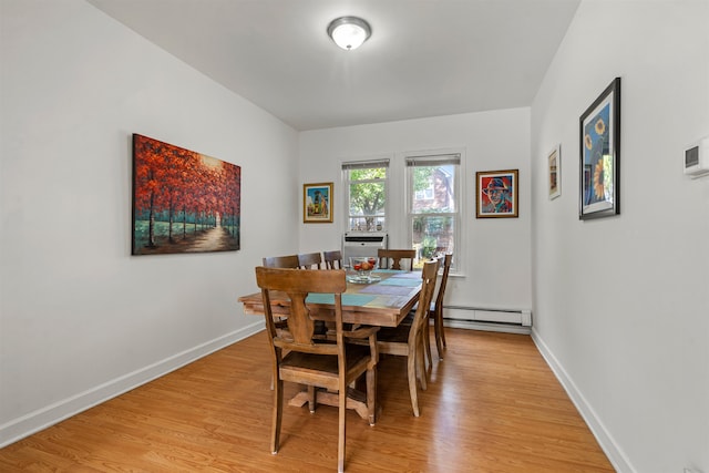 dining space with light hardwood / wood-style floors and a baseboard heating unit