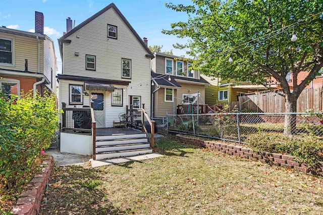 rear view of house featuring a wooden deck and a yard