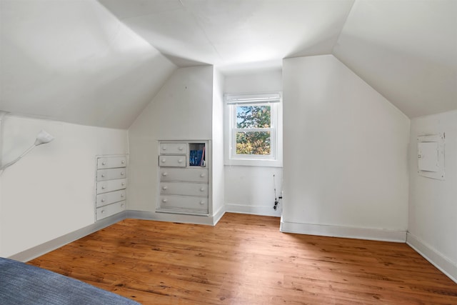 additional living space featuring electric panel, hardwood / wood-style flooring, and lofted ceiling