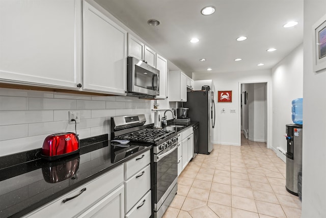 kitchen featuring white cabinetry, appliances with stainless steel finishes, backsplash, light tile patterned floors, and sink