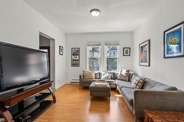 living room with a baseboard heating unit and light hardwood / wood-style flooring