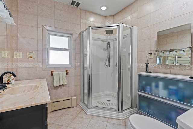 bathroom with a shower with shower door, tile patterned flooring, a baseboard radiator, and tile walls