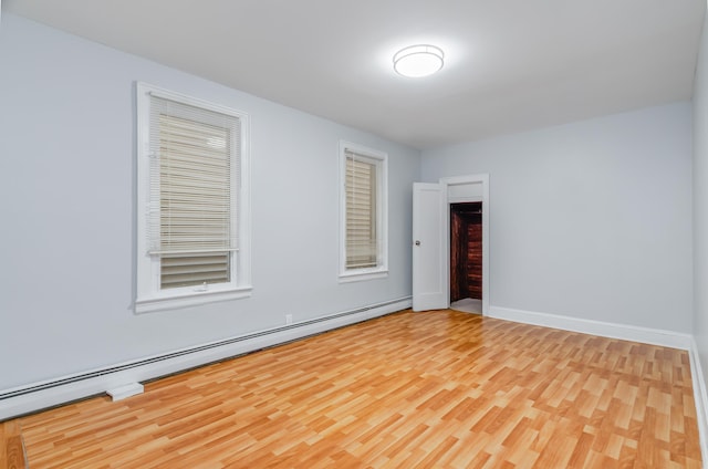 unfurnished room featuring a baseboard radiator, wood finished floors, and baseboards