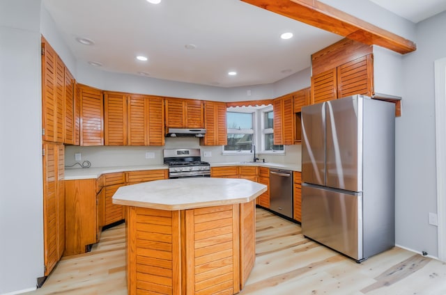 kitchen featuring light countertops, appliances with stainless steel finishes, a kitchen island, and light wood-style flooring