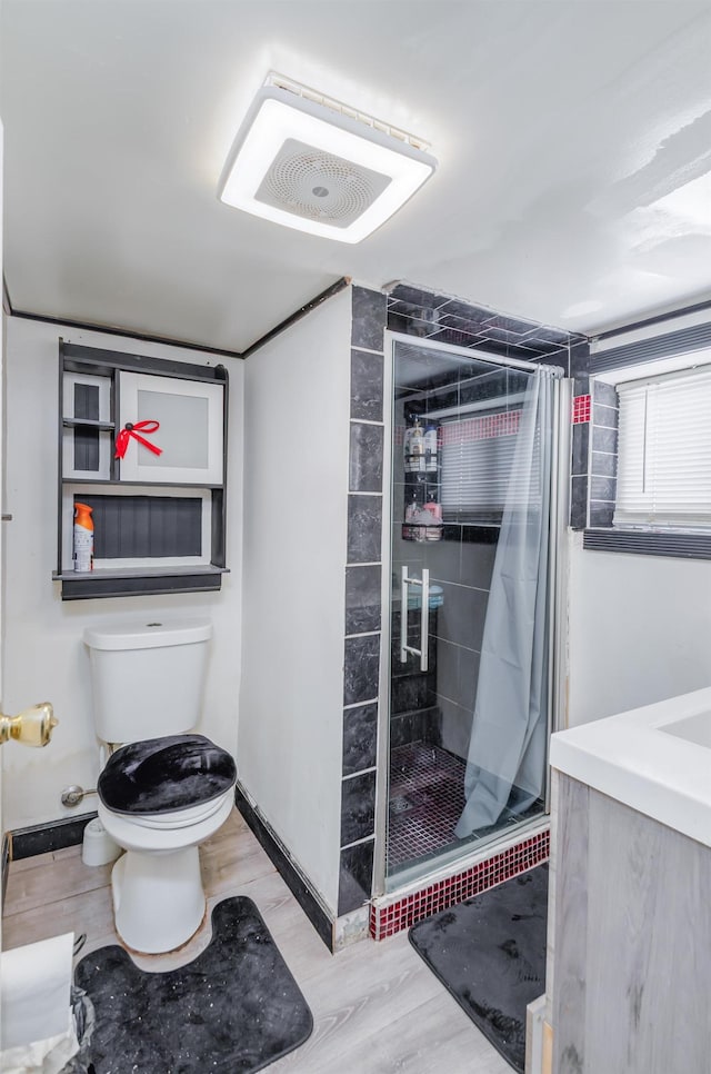 bathroom featuring a stall shower, wood finished floors, and toilet