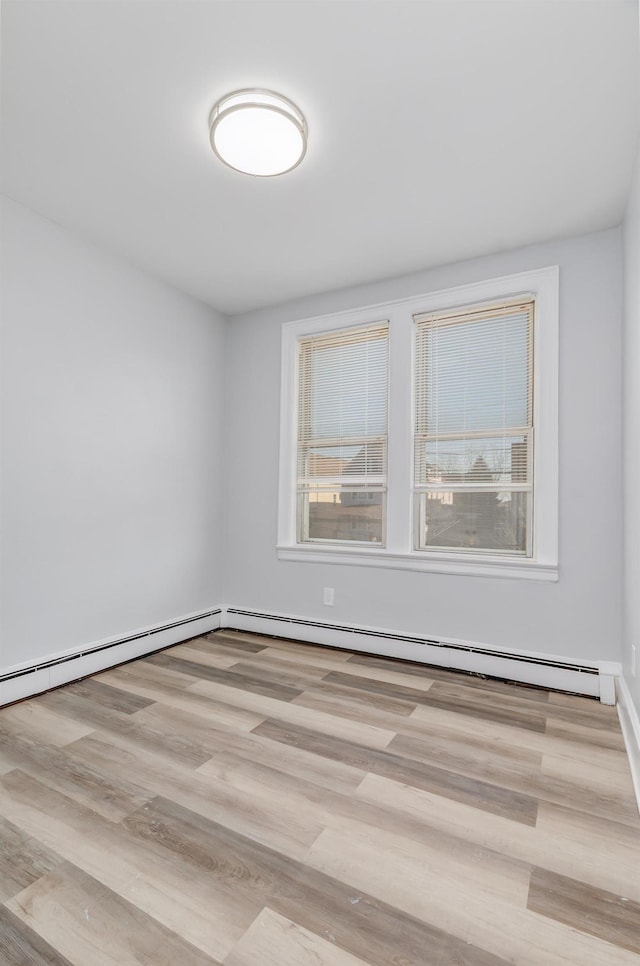 spare room with a baseboard heating unit, plenty of natural light, and wood finished floors