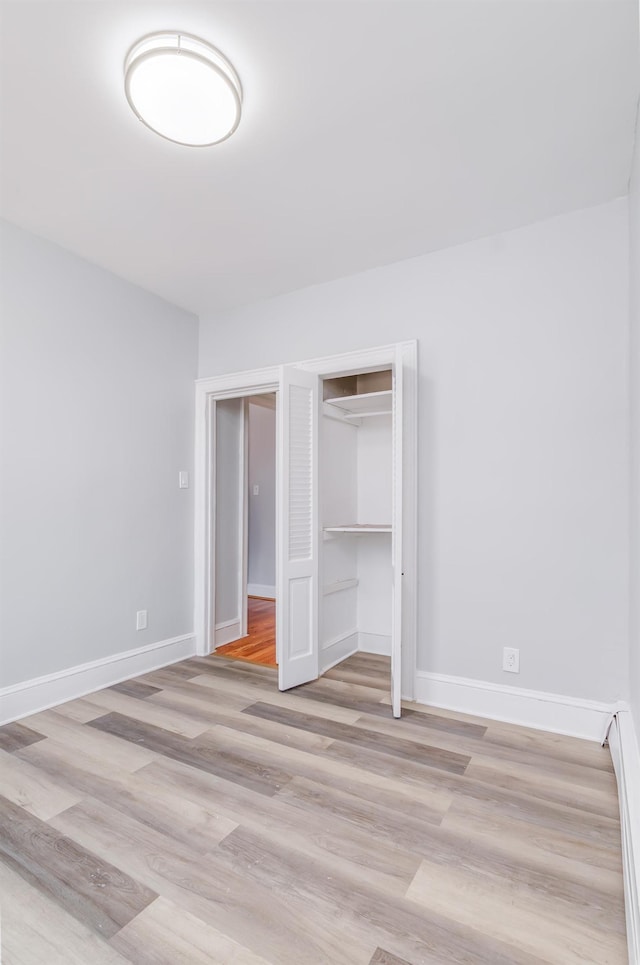 unfurnished bedroom with light wood-type flooring, baseboards, and a closet