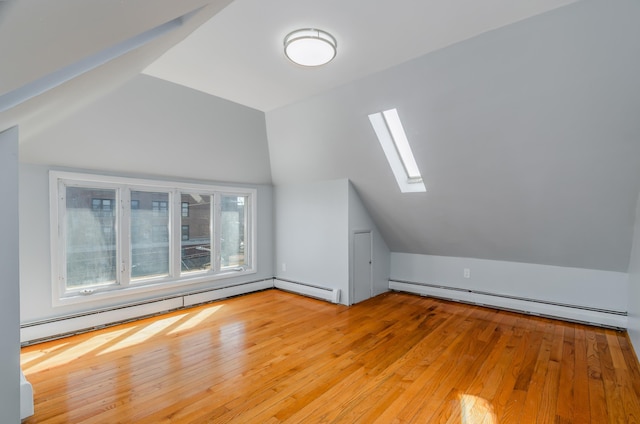 bonus room featuring a baseboard heating unit, vaulted ceiling with skylight, and light wood-type flooring