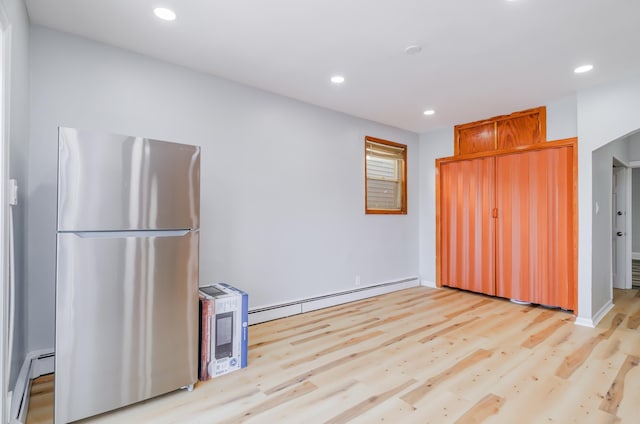 kitchen featuring freestanding refrigerator, light wood-style flooring, baseboard heating, and recessed lighting