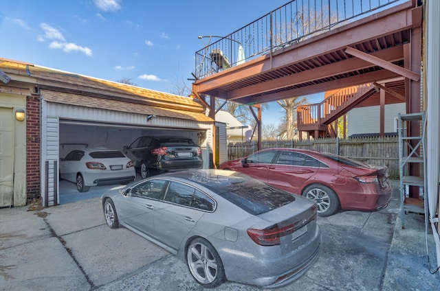 view of vehicle parking with a garage, concrete driveway, fence, and a carport