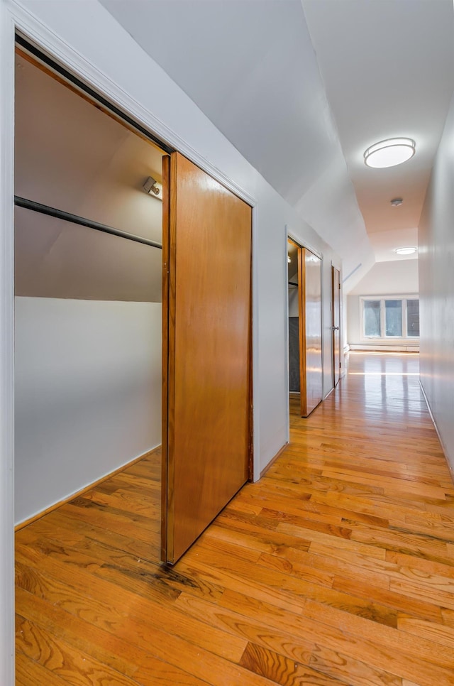 hall with lofted ceiling and light wood-style floors