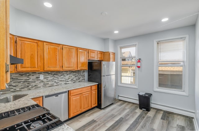 kitchen with a baseboard heating unit, stainless steel appliances, backsplash, and light stone countertops