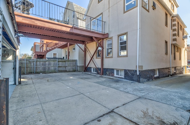 exterior space featuring stairway, fence, and stucco siding