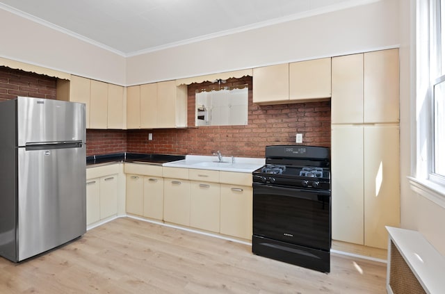 71 W 17th St, Bayonne, NJ 07002 - kitchen featuring freestanding refrigerator, black range with gas cooktop, cream cabinetry, ornamental molding, and light wood-type flooring