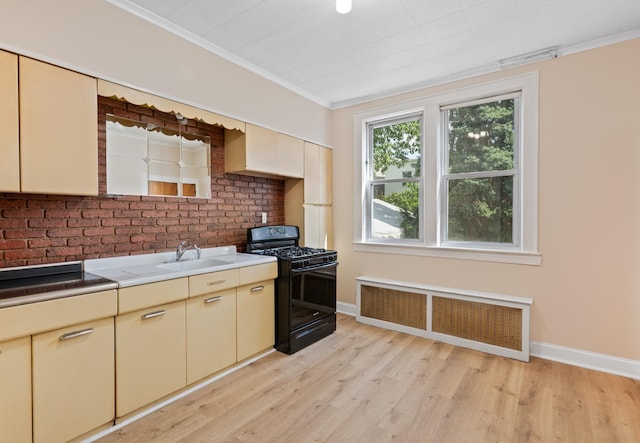 71 W 17th St, Bayonne, NJ 07002 - kitchen featuring black gas range oven, radiator heating unit, cream cabinetry, light wood finished floors, and ornamental molding