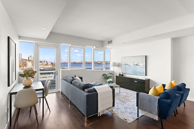 living room with dark hardwood / wood-style flooring and a water view