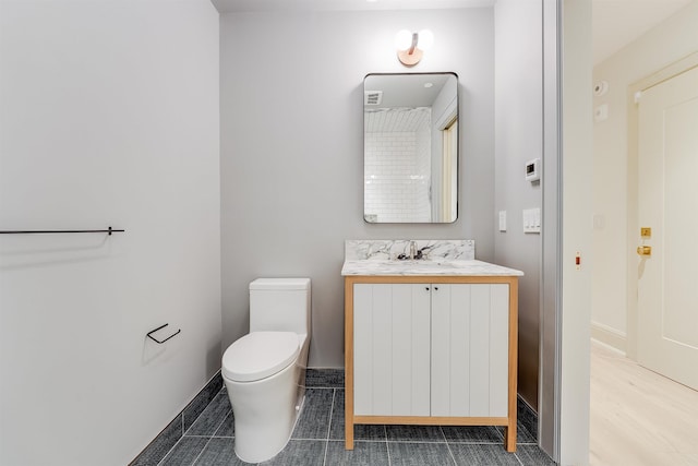 bathroom with toilet, vanity, baseboards, and tile patterned flooring