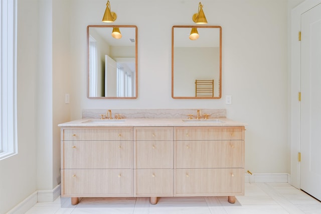 bathroom with double vanity, baseboards, and a sink