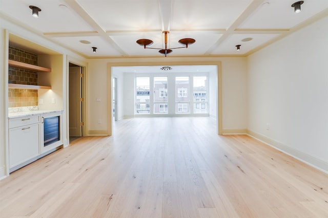 unfurnished living room featuring coffered ceiling, light wood-style floors, and baseboards