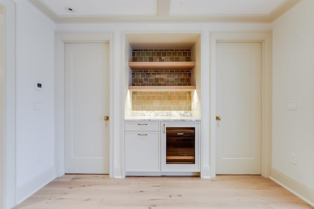 bar with light wood-style flooring, baseboards, crown molding, and wine cooler