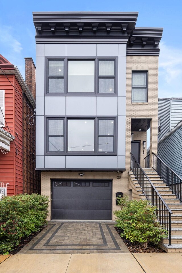 23 Manhattan Ave Unit 1, Jersey City, NJ 07307 - view of front facade featuring a garage, brick siding, stairway, and driveway