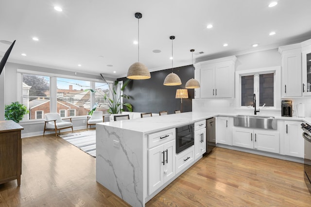 23 Manhattan Ave Unit 1, Jersey City, NJ 07307 - kitchen with a sink, a peninsula, white cabinetry, crown molding, and pendant lighting