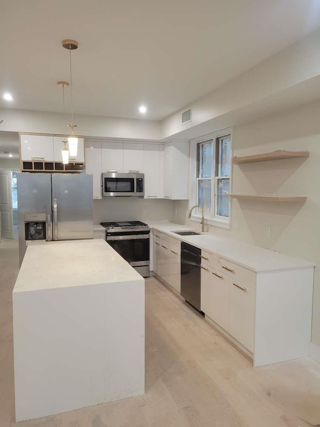 kitchen featuring sink, hanging light fixtures, light hardwood / wood-style floors, white cabinets, and appliances with stainless steel finishes