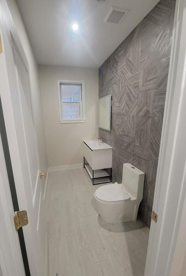 bathroom featuring vanity, hardwood / wood-style flooring, toilet, and tile walls