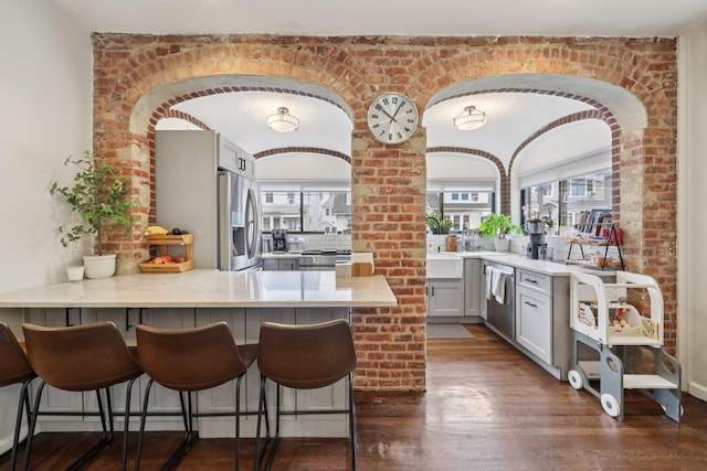 7619 5th Ave, North Bergen, NJ 07047 - kitchen with appliances with stainless steel finishes, a peninsula, dark wood-style flooring, and arched walkways