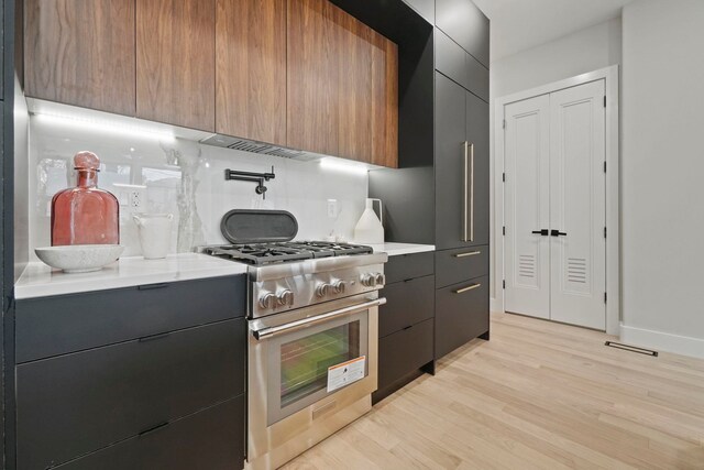 81 Webster Ave Unit 1, Jersey City, NJ 07307 - kitchen with modern cabinets, high end stove, light wood-type flooring, decorative backsplash, and dark cabinets