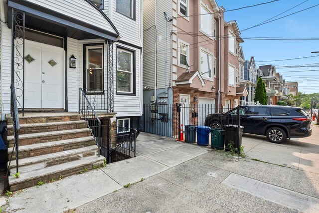 48 Armstrong Ave, Jersey City, NJ 07305 - view of exterior entry with driveway, a garage, and a residential view