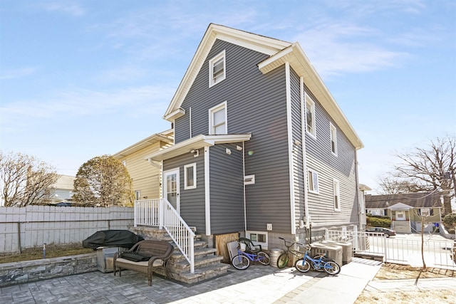 rear view of property with a patio, central AC unit, and fence