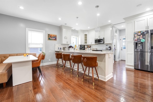 kitchen featuring recessed lighting, stainless steel appliances, a kitchen breakfast bar, and dark wood finished floors