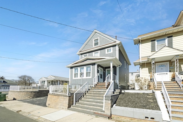 american foursquare style home featuring stairs, a porch, and fence