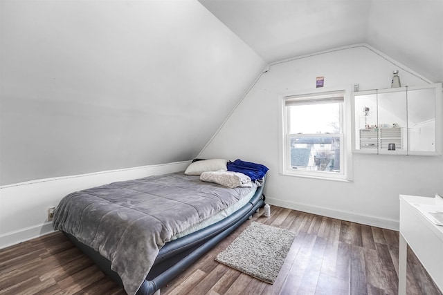 bedroom featuring baseboards, lofted ceiling, and wood finished floors