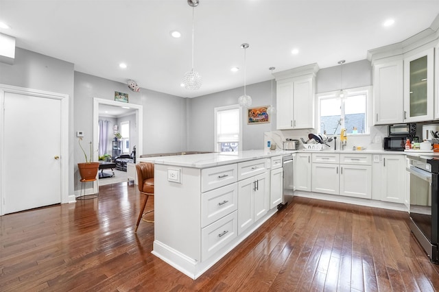 kitchen featuring white cabinets, a peninsula, dark wood-type flooring, and a kitchen breakfast bar