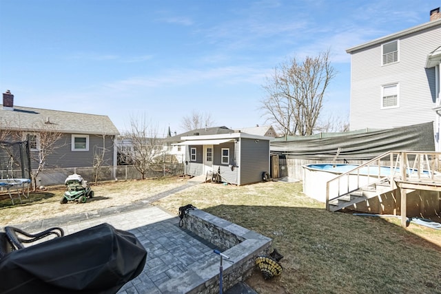 view of yard featuring a fenced in pool, a trampoline, a fenced backyard, an outdoor structure, and a patio