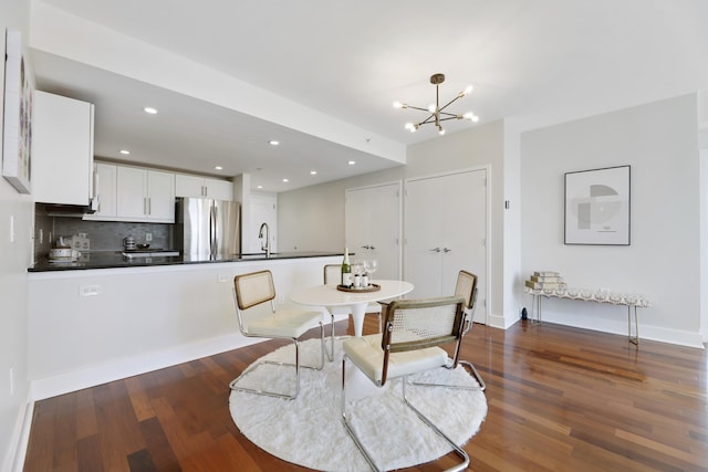 dining space with an inviting chandelier, dark wood-type flooring, and sink