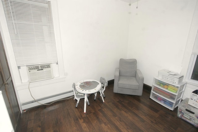 sitting room featuring a baseboard heating unit, wood finished floors, and cooling unit