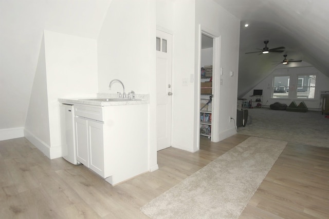 bathroom with vaulted ceiling, a sink, a ceiling fan, wood finished floors, and baseboards