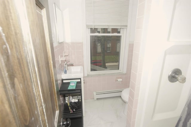bathroom with tile walls, a baseboard radiator, a sink, toilet, and marble look tile flooring