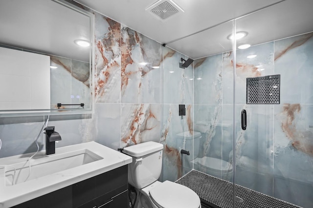 bathroom with tile walls, vanity, a shower with door, and toilet