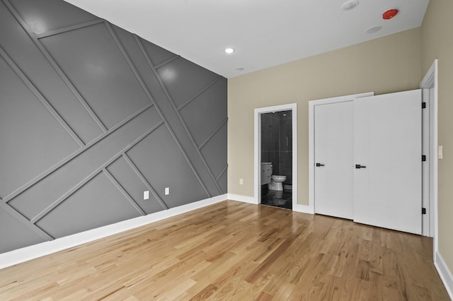 unfurnished bedroom featuring wood-type flooring and ensuite bathroom