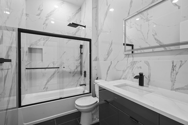 full bathroom featuring tile walls, enclosed tub / shower combo, vanity, and toilet