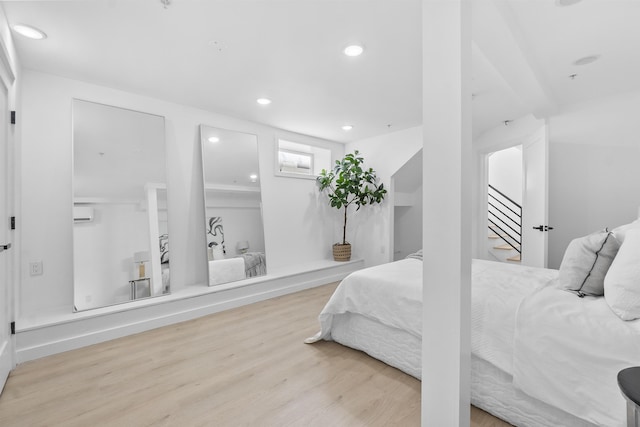 bedroom with a wall unit AC and light wood-type flooring