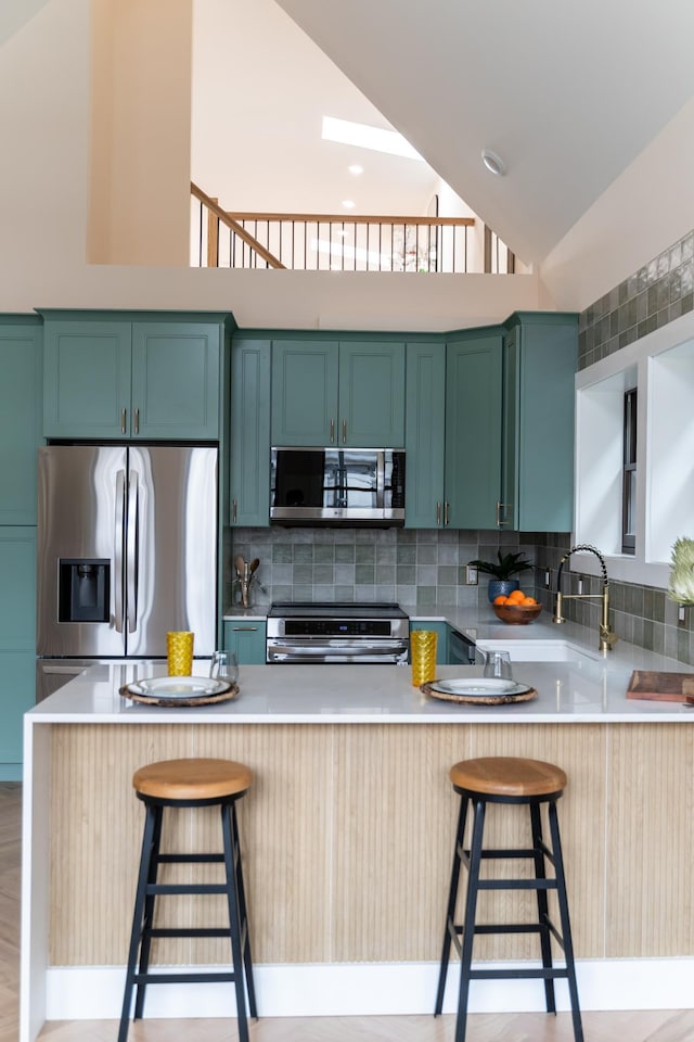 247 Harrison Ave Unit 2, Jersey City, NJ 07304 - kitchen featuring stainless steel appliances, a peninsula, backsplash, high vaulted ceiling, and light countertops